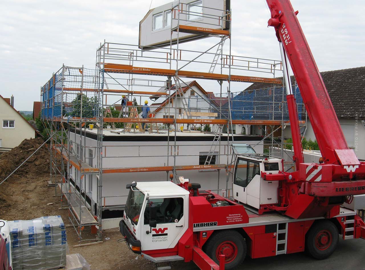 fertighaus-aufbau-firma-empfehlung-tag-2-baukran-hebt-wantteil-betonteil-fertigteil-baustelle-stahlseil-schnell-guenstig