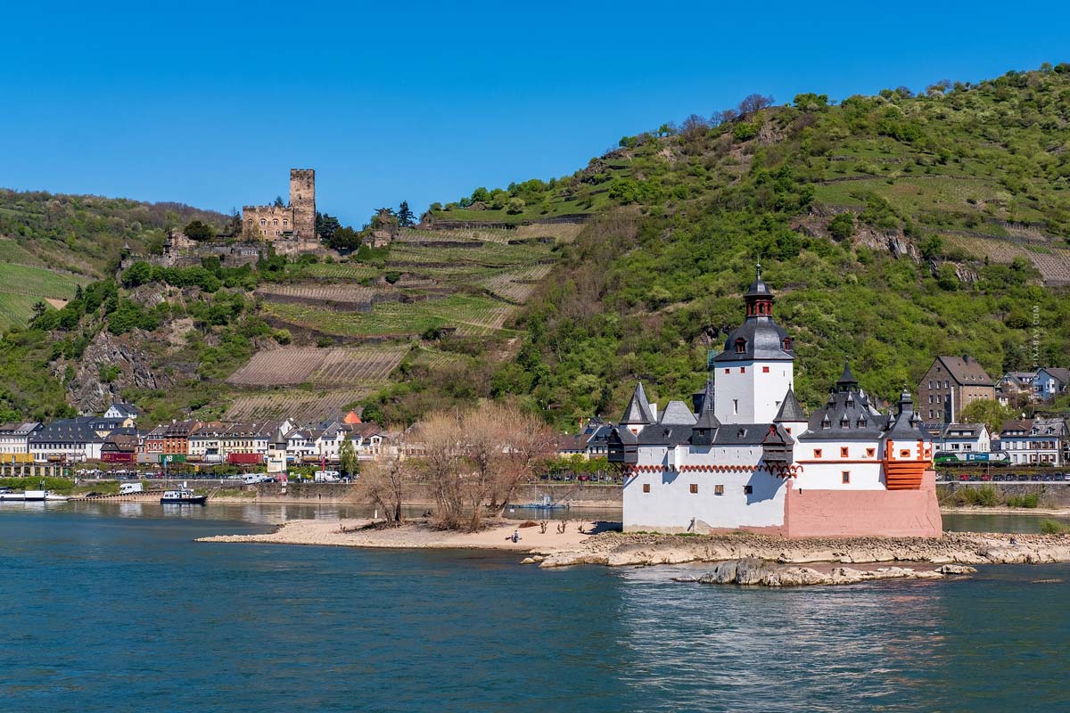 Blick auf den Rhein inmitten des Rheinlandes mit unberührter Natur, viel Wald, Burg und kleinen Häusern