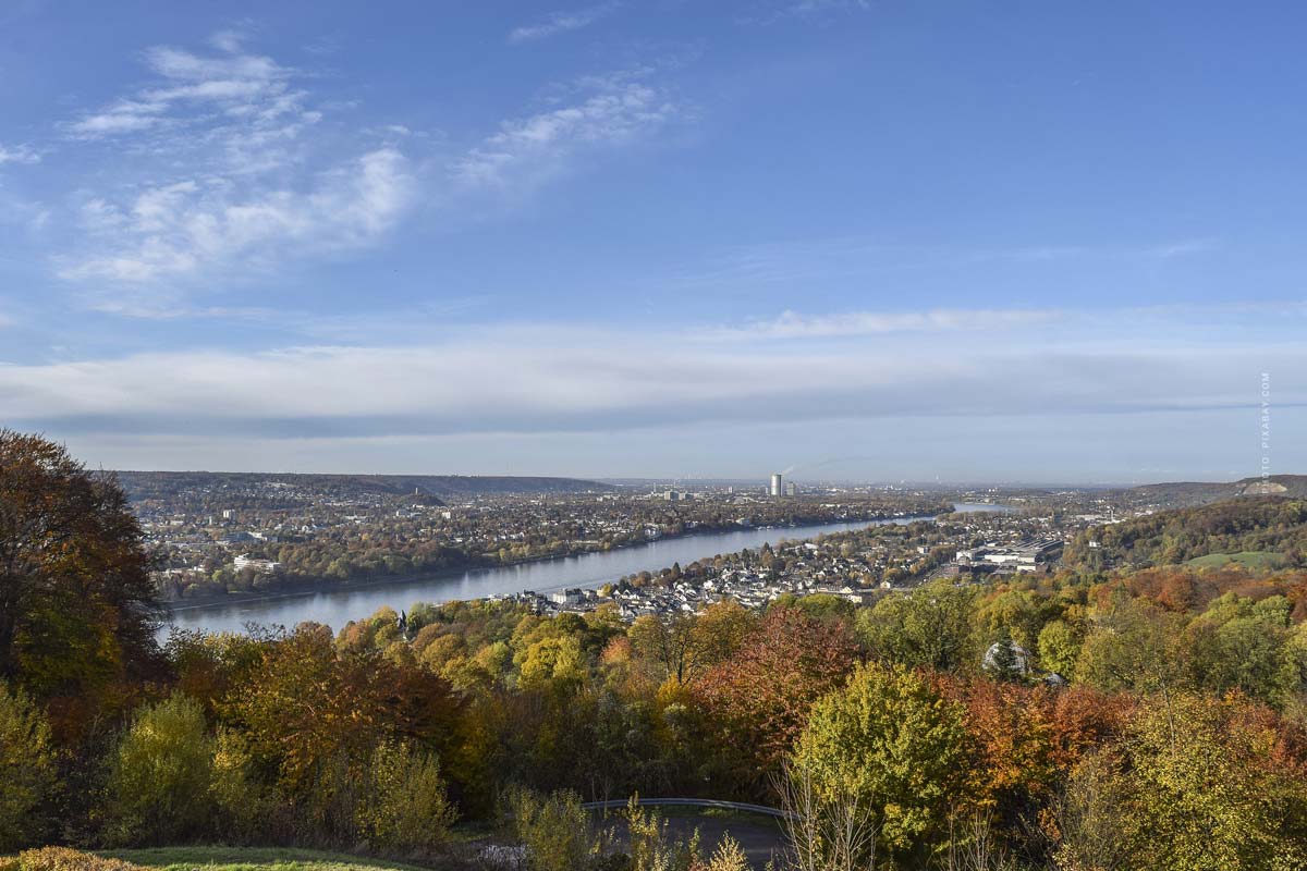Blick auf den Rhein inmitten des Rheinlandes umgeben von Wald und strahlend blauem Himmel