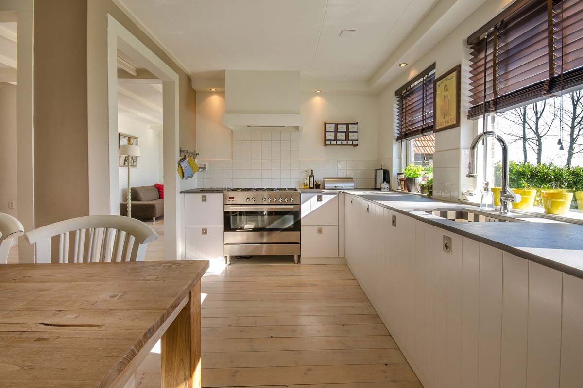 Moderne und gemütliche Küche mit Holzboden und großen, hellen Fenstern