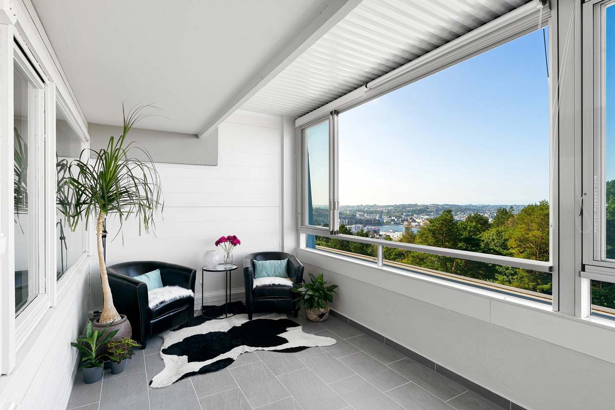 Heller Balkon mit Topfpflanze und zwei Stühlen und grandioser Aussicht auf die Stadt