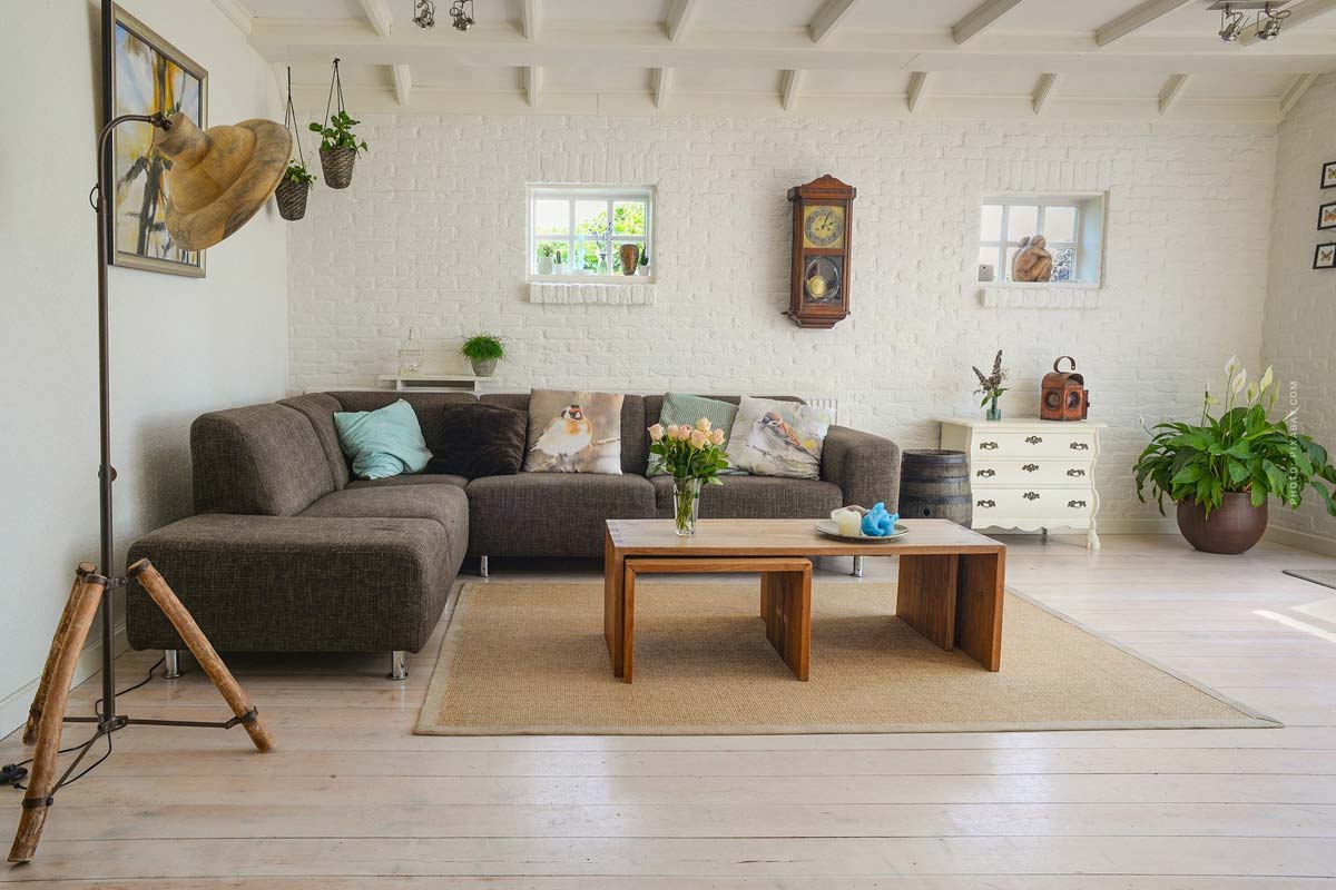 Wohnzimmer mit heller Einrichtung und brauner Couch